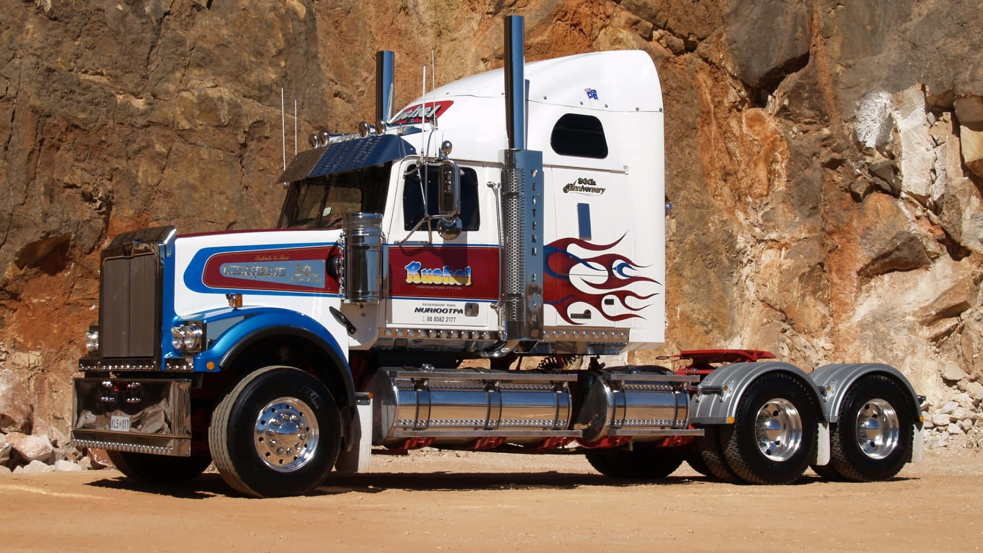 A Large Truck Parked In Front Of A Rock