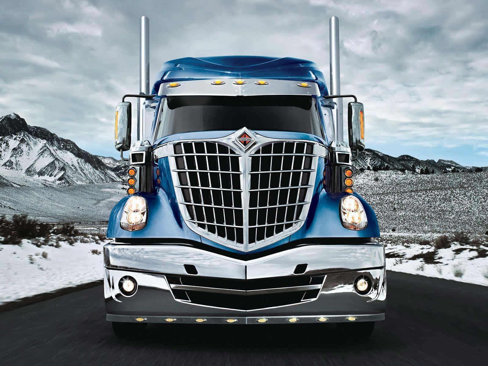 A Blue Semi Truck Driving Down A Snowy Road