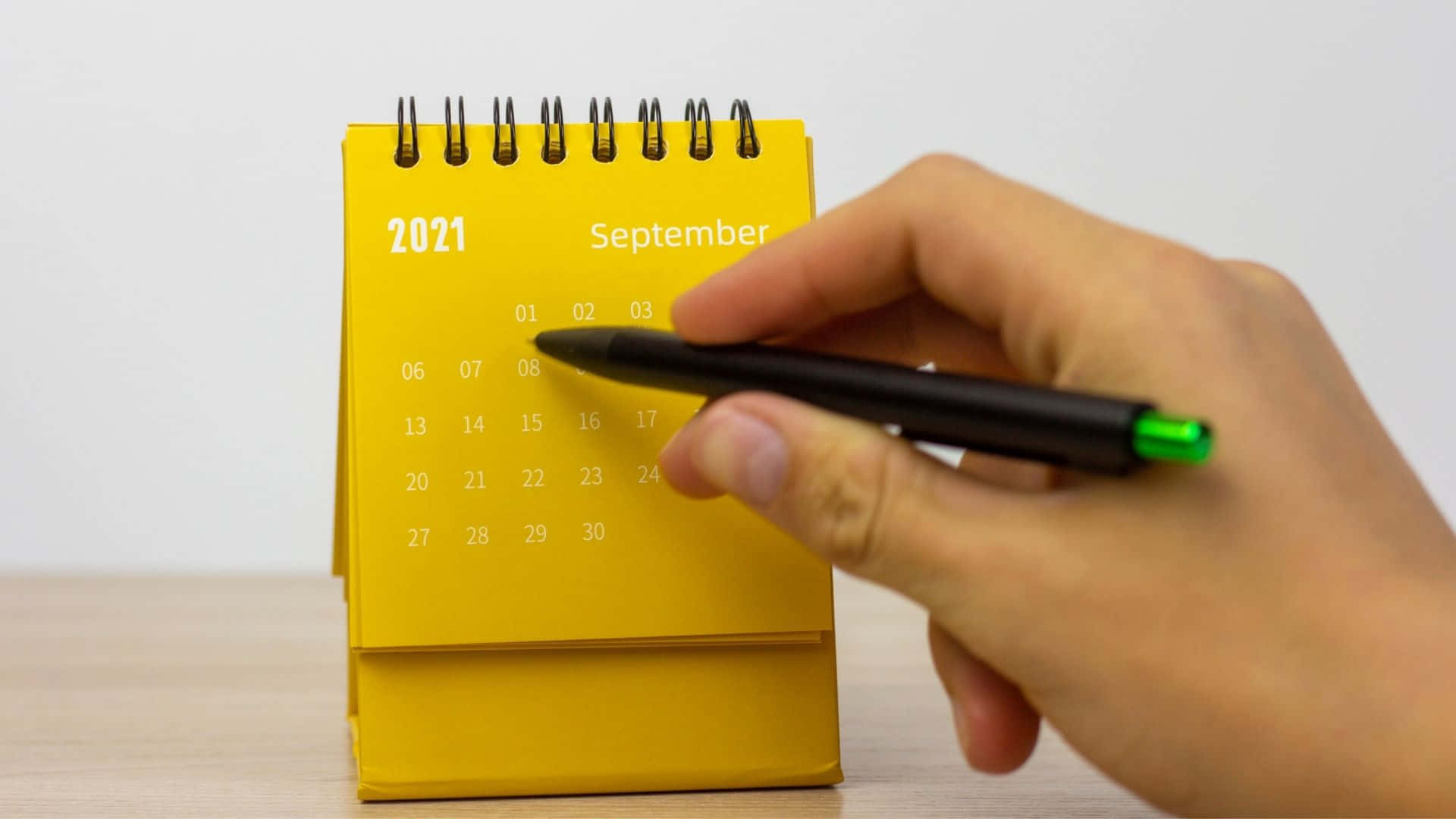 En person holder en gul kalender med en pen. Wallpaper