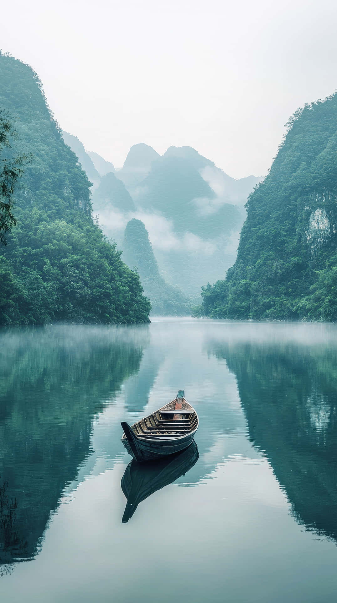 Serene Wooden Boat Floating On A Misty Lake Surrounded By Lush Mountains Wallpaper