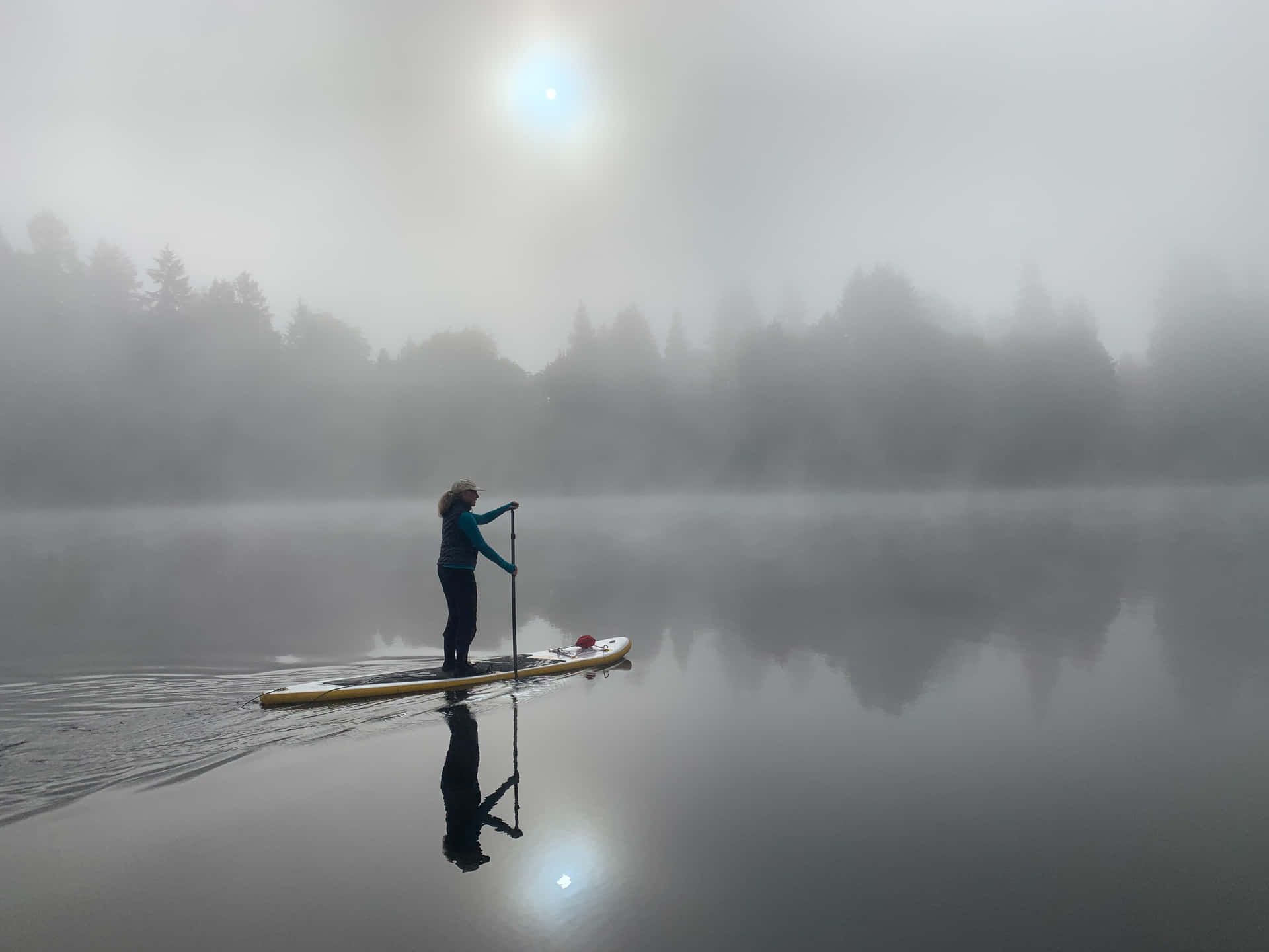 A Person Paddle Boarding In The Fog Wallpaper