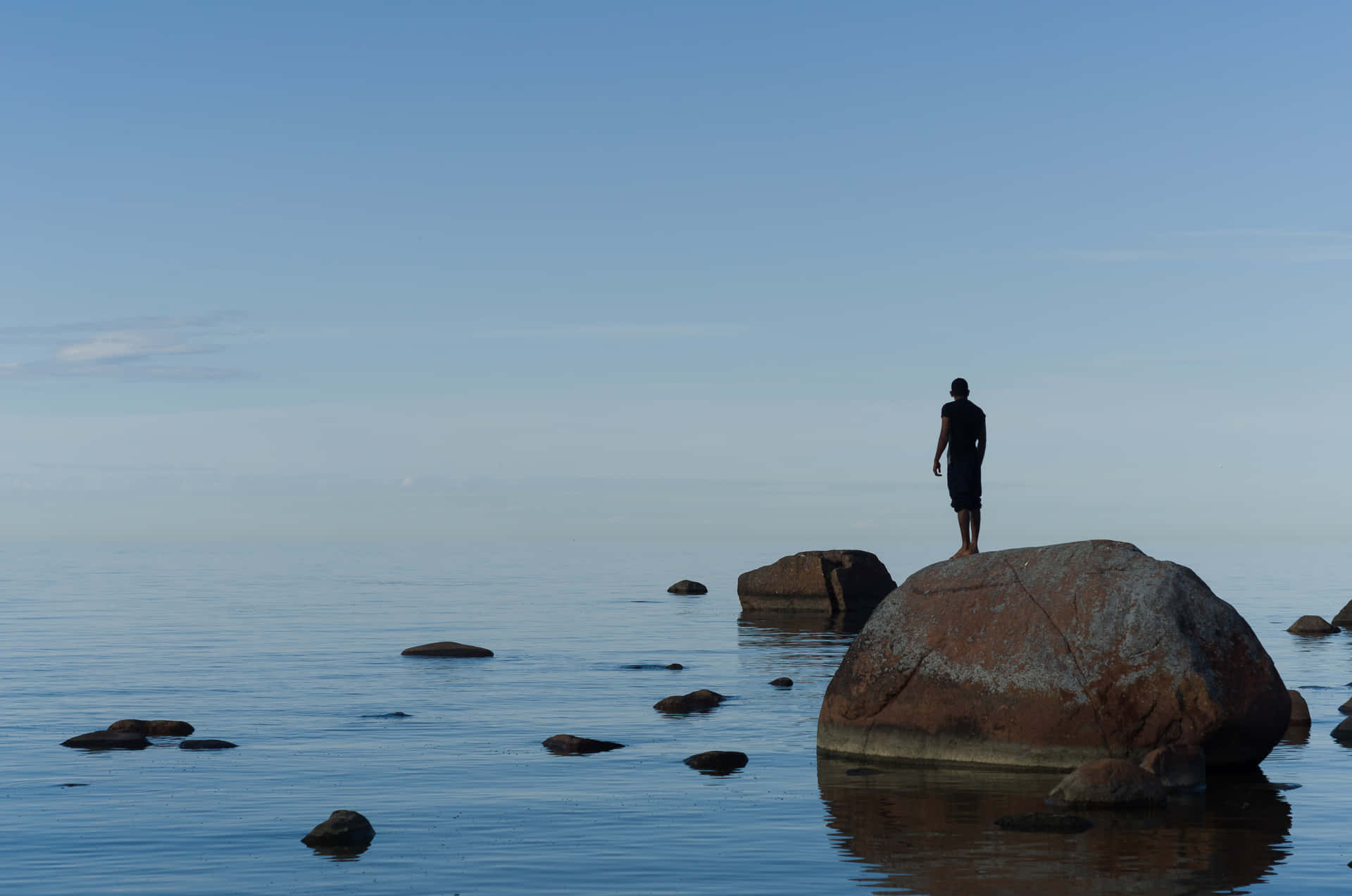 a person standing on a rock in the water Wallpaper