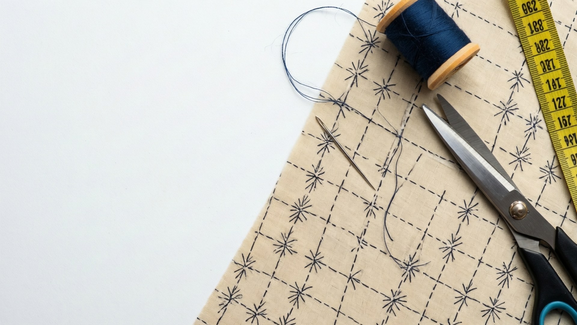 Flat lay of a sewing needle on pattern paper with scissors and tape.
