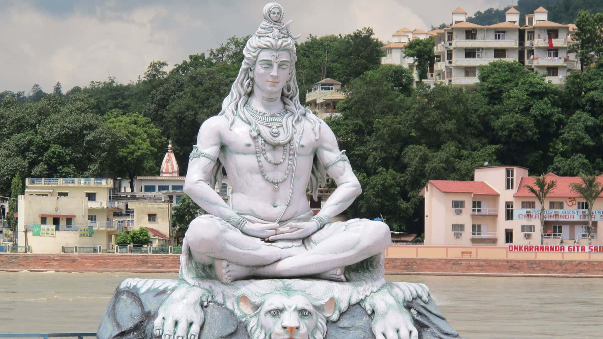 A Statue Of Lord Shiva Sitting On Top Of A River