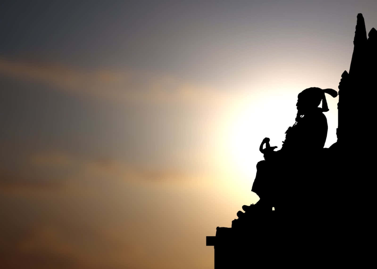 Silhouette Of A Man Sitting On Top Of A Statue