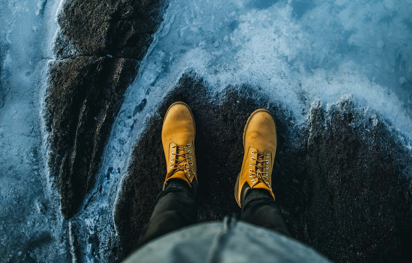 Person Standing On Ice In Yellow Boots