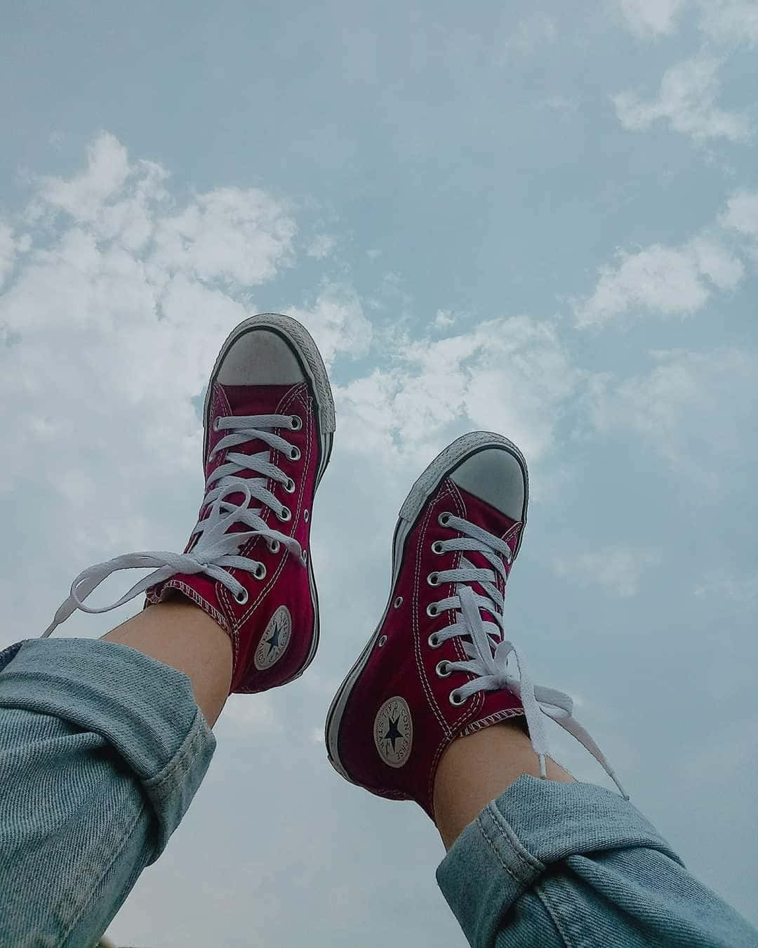 A Person's Feet In Red Converse