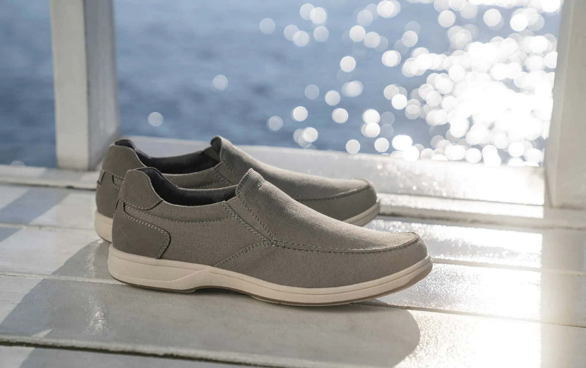 A Pair Of Grey Slip On Shoes On A Wooden Deck