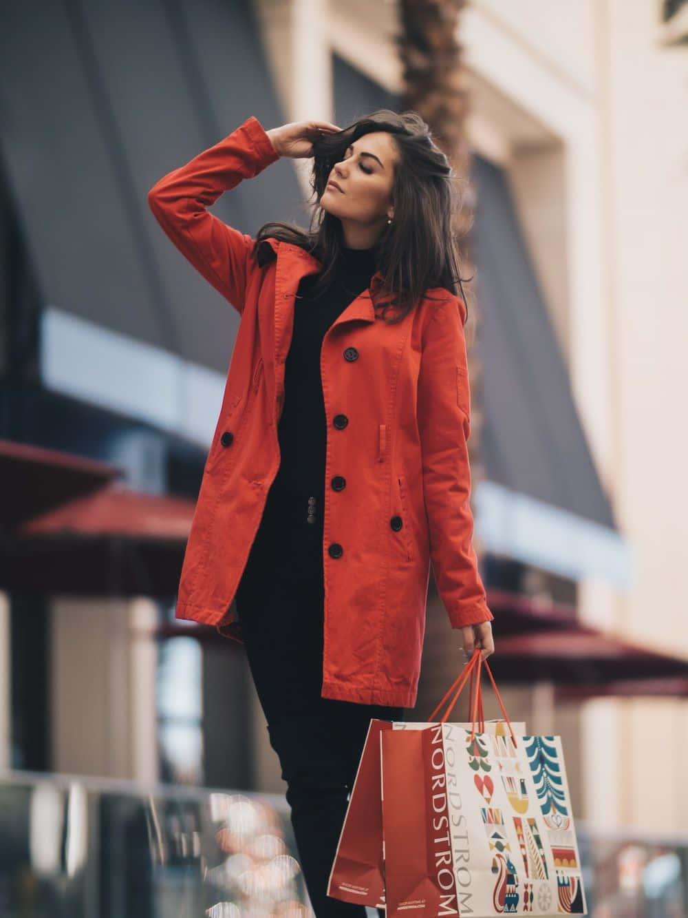 A Woman In A Red Coat Holding Shopping Bags
