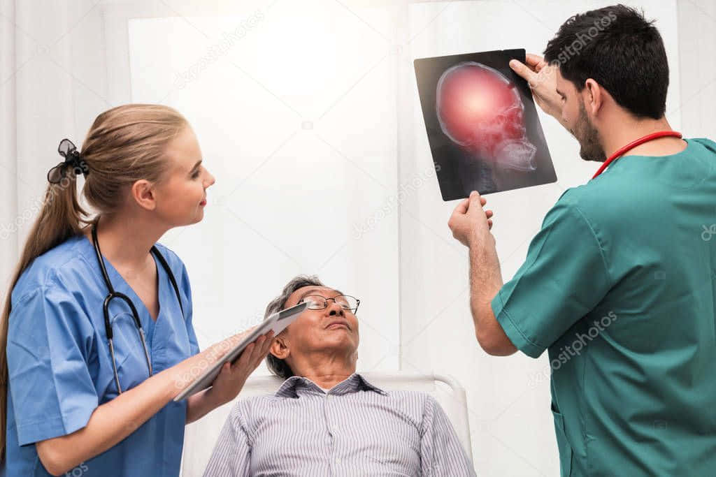 A Doctor Is Looking At An X - Ray Of An Elderly Patient