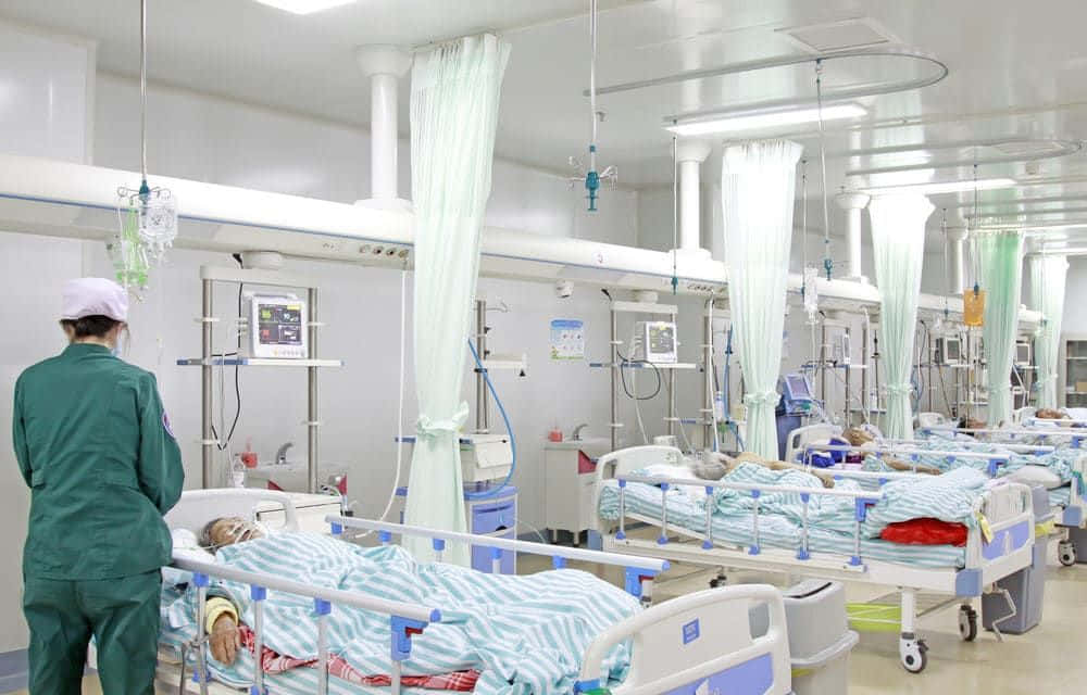 A Hospital Room With Many Beds And A Nurse