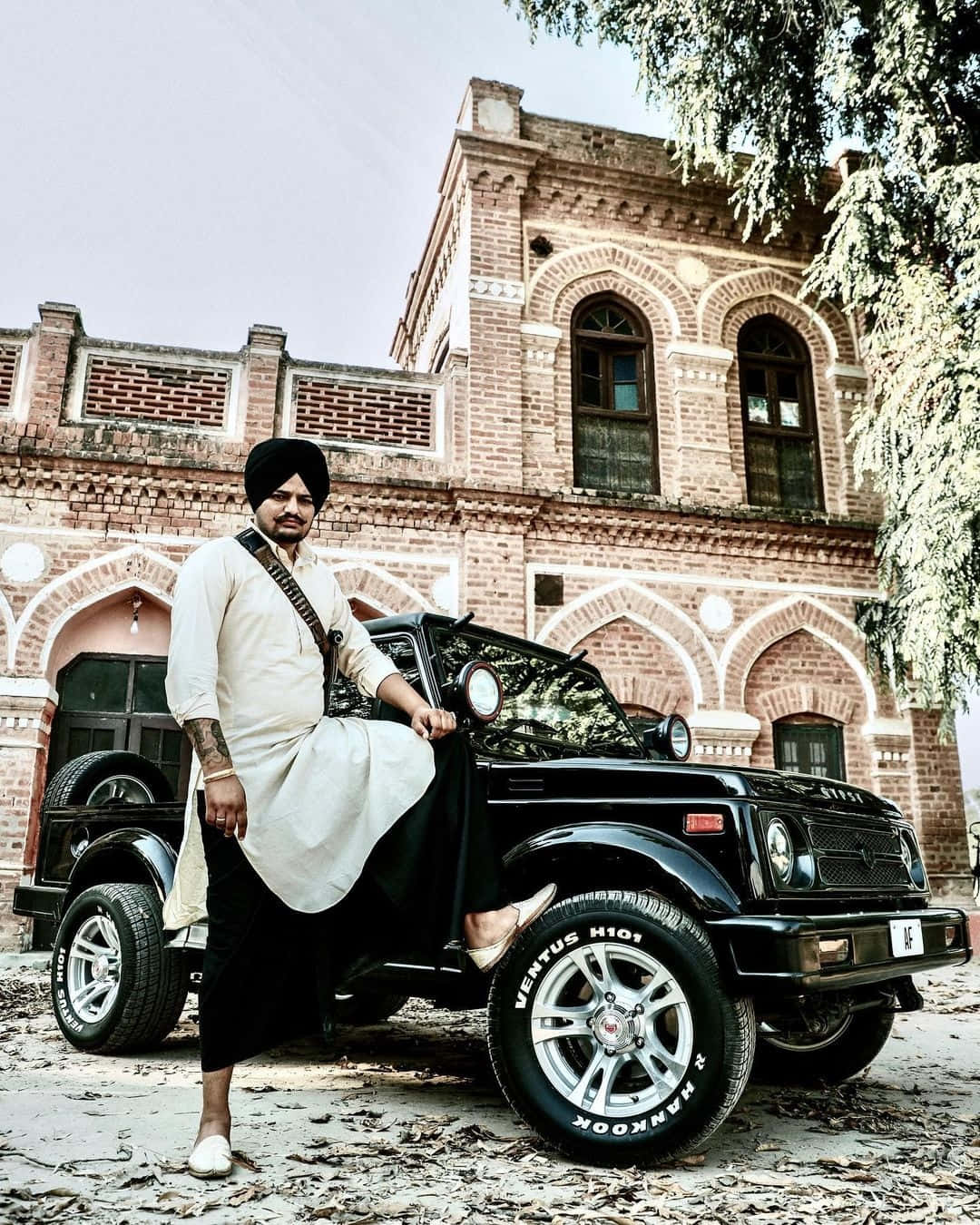 A Man In A Turban Standing Next To A Jeep