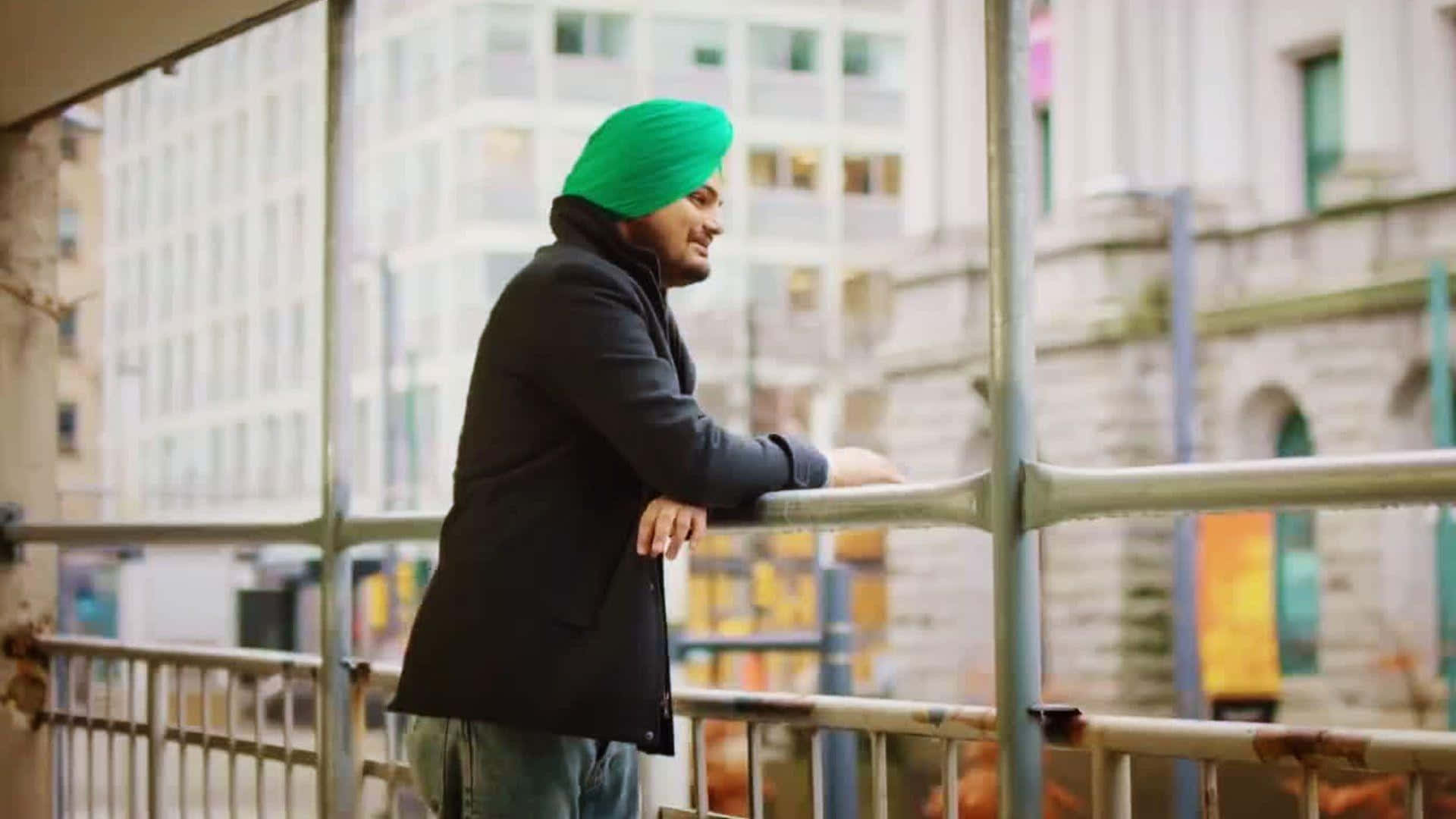 A Man In A Green Turban Leaning On A Railing