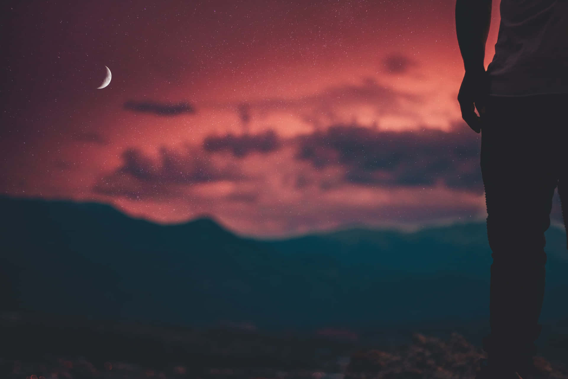 A Man Standing On A Mountain Looking At The Moon And Stars