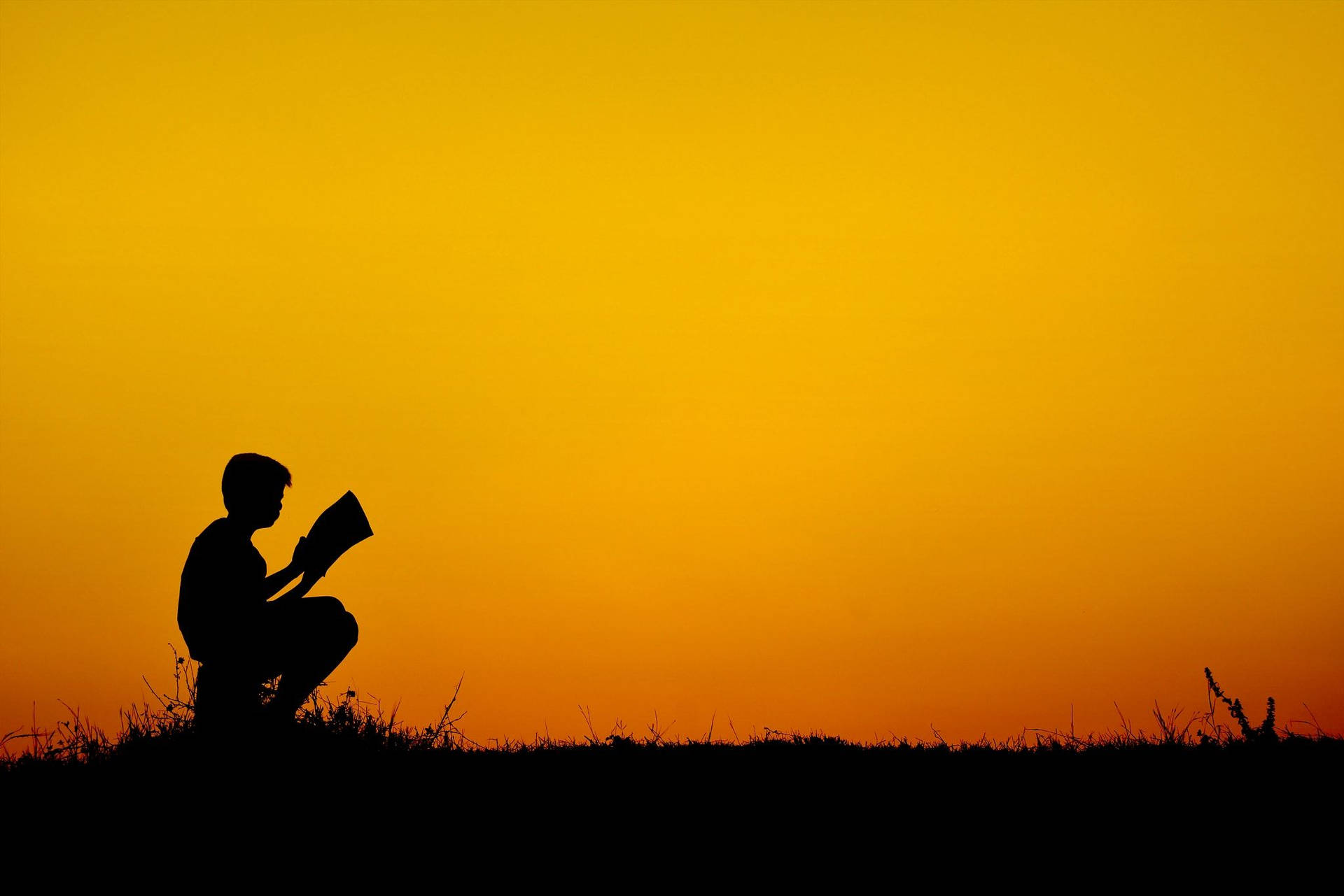Silhouet af dreng læser bog på stjernehimmel Wallpaper