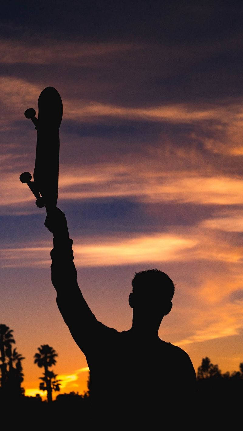 Silhouette Of Man Holding Skateboard Iphone Wallpaper