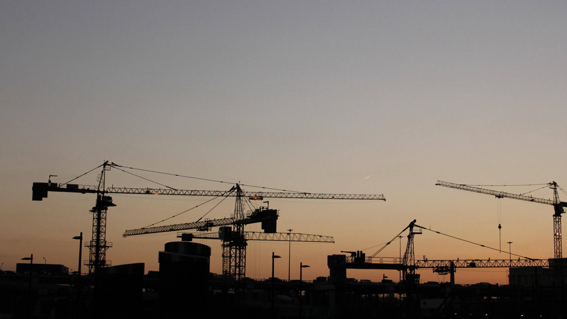Silhouetted Construction Cranes During Sunset Wallpaper