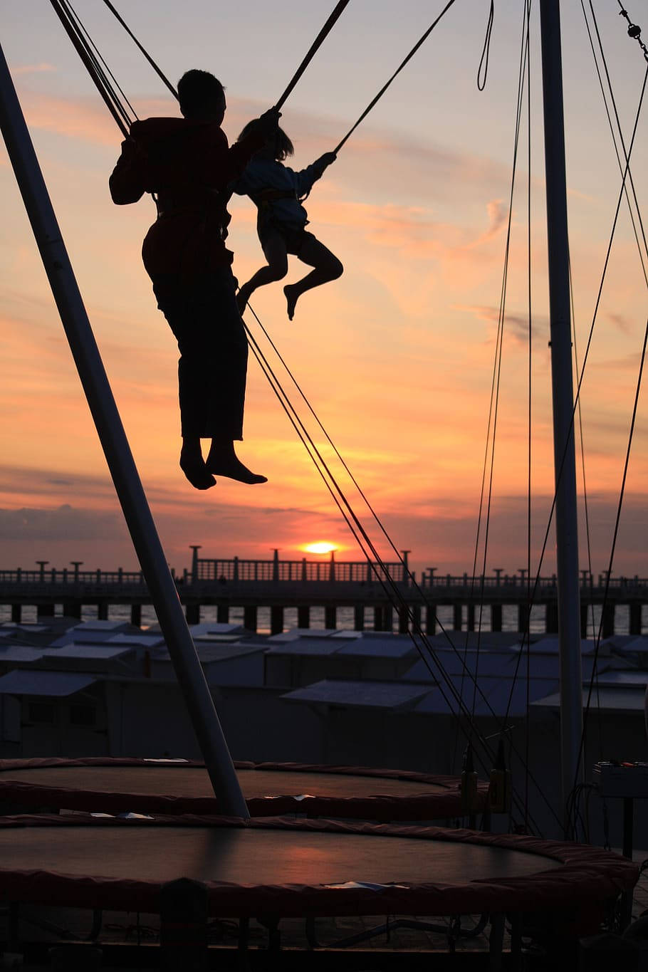 Silhuet af far og søn hopper fra trampolin Wallpaper
