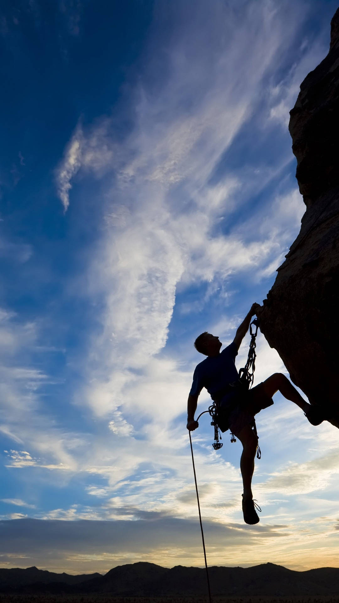 Silhouetted Man Climbing A Rock Wallpaper