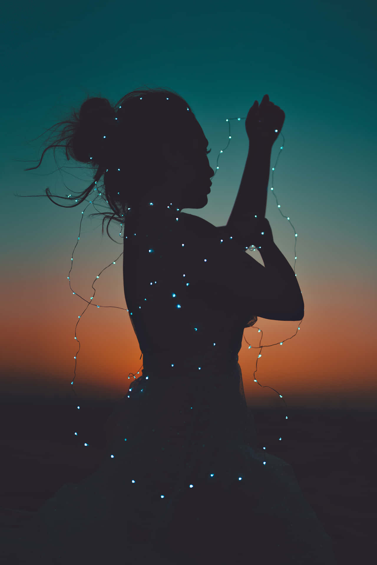 Silhouetteof Womanwith Fairy Lightsat Twilight Wallpaper