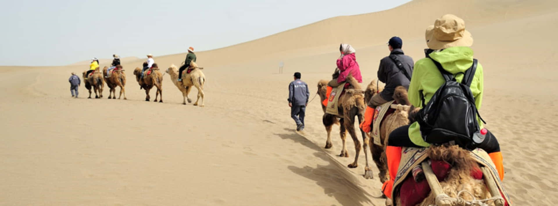Einegruppe Von Menschen, Die Auf Kamelen Durch Die Wüste Reiten.
