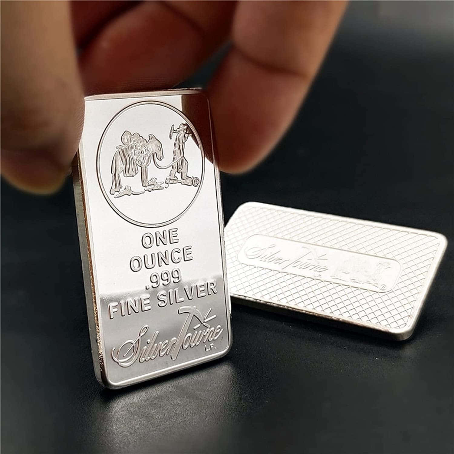 A Person Holding A Silver Bar Next To A Small Box