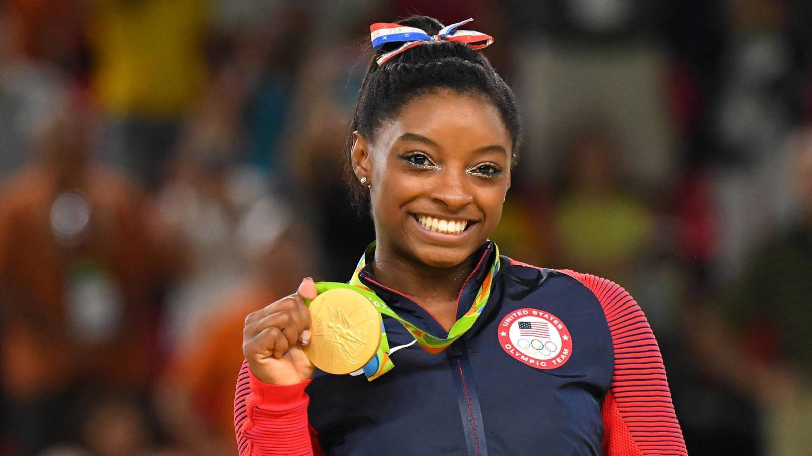 Simone Biles Holding A Gold Medal And Smiling Wallpaper