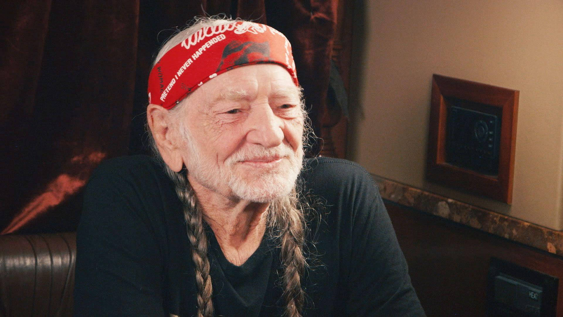 Iconic Singer Willie Nelson Posing with Braided Hair and Bandana Wallpaper