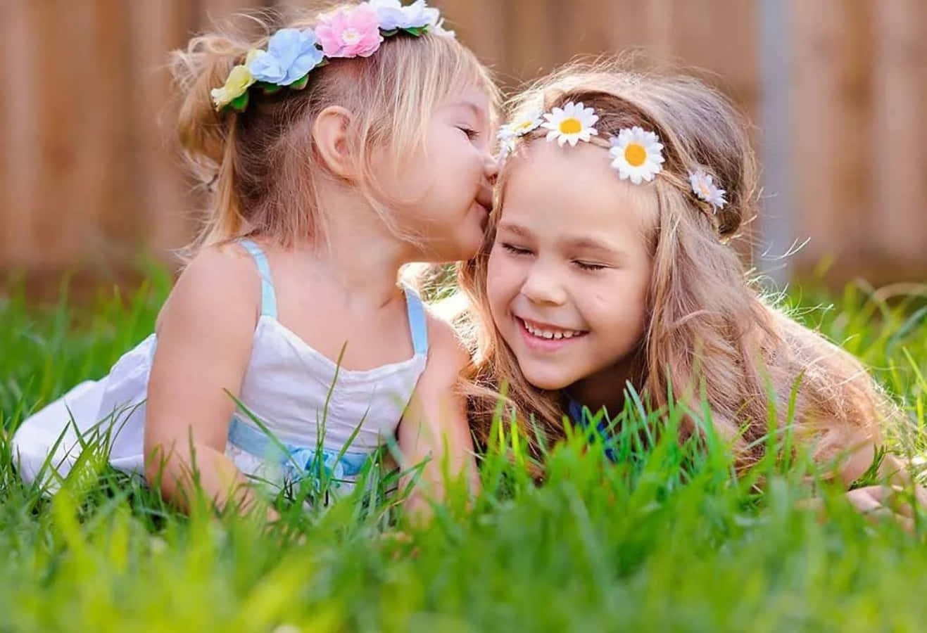 Two Little Girls Kissing In The Grass
