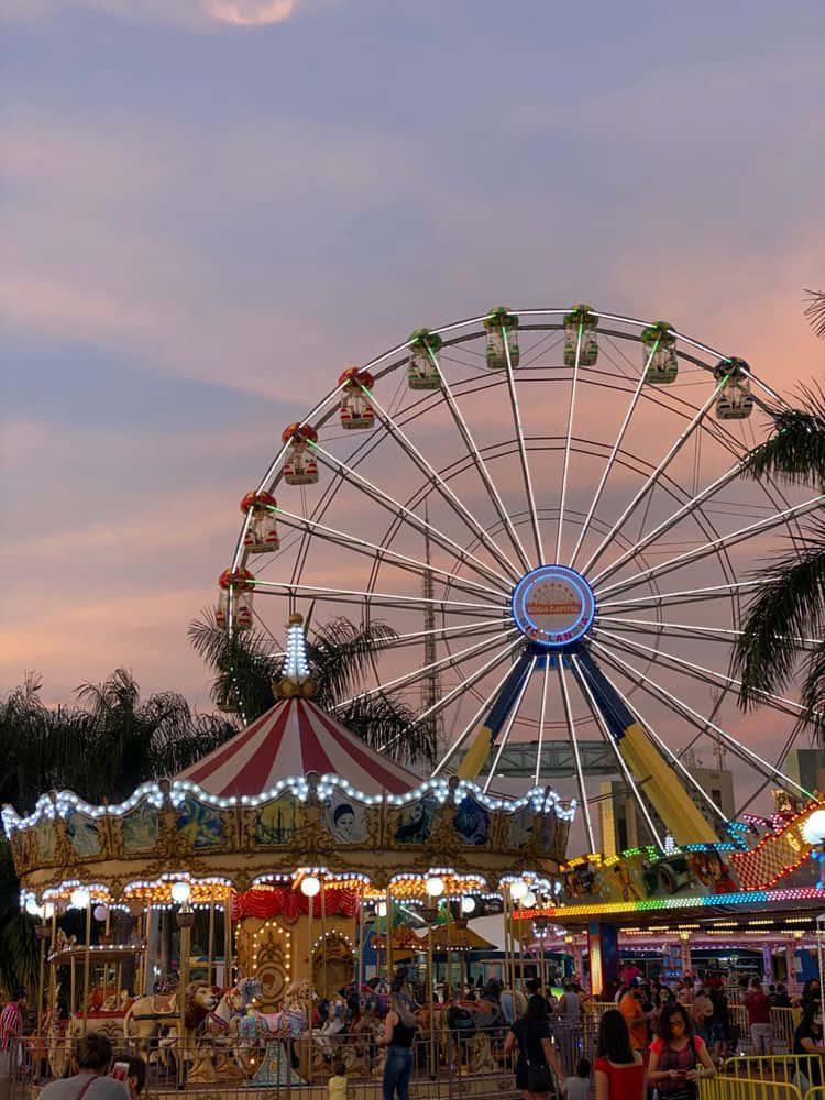 A Ferris Wheel And Carnival Rides At Sunset