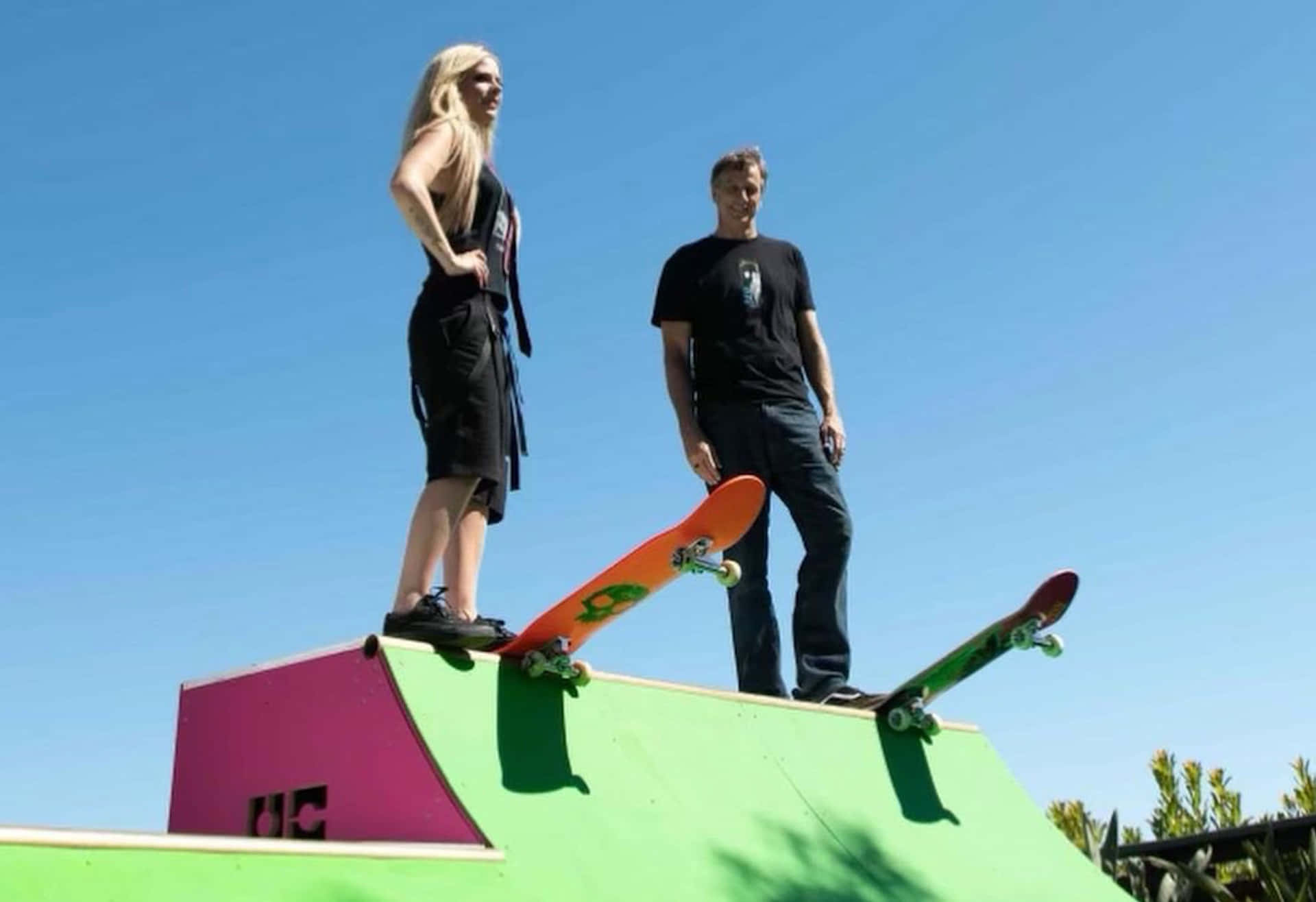 Two People Standing On Top Of A Skateboard Ramp