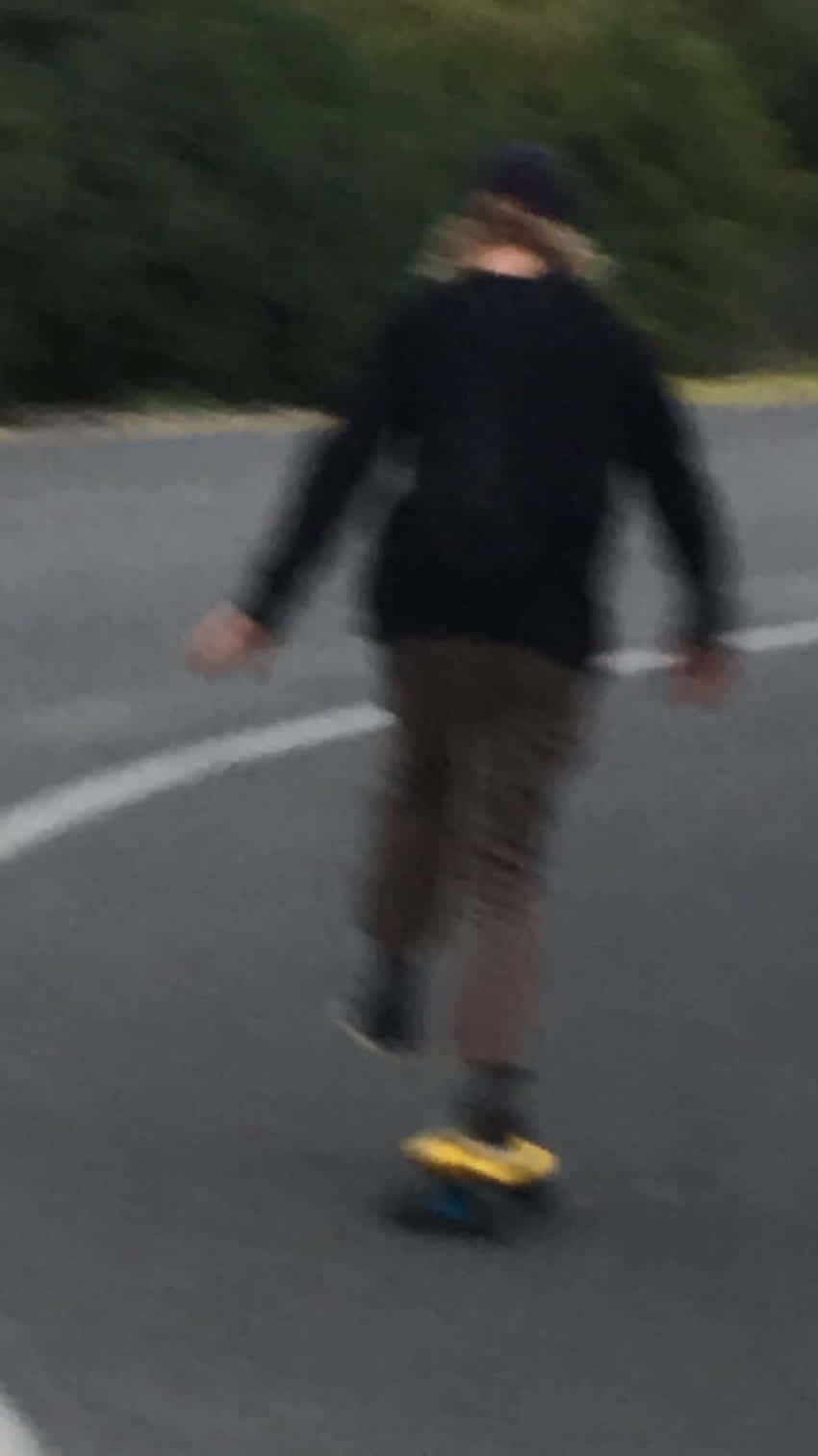 A Person Riding A Skateboard Down A Road Wallpaper