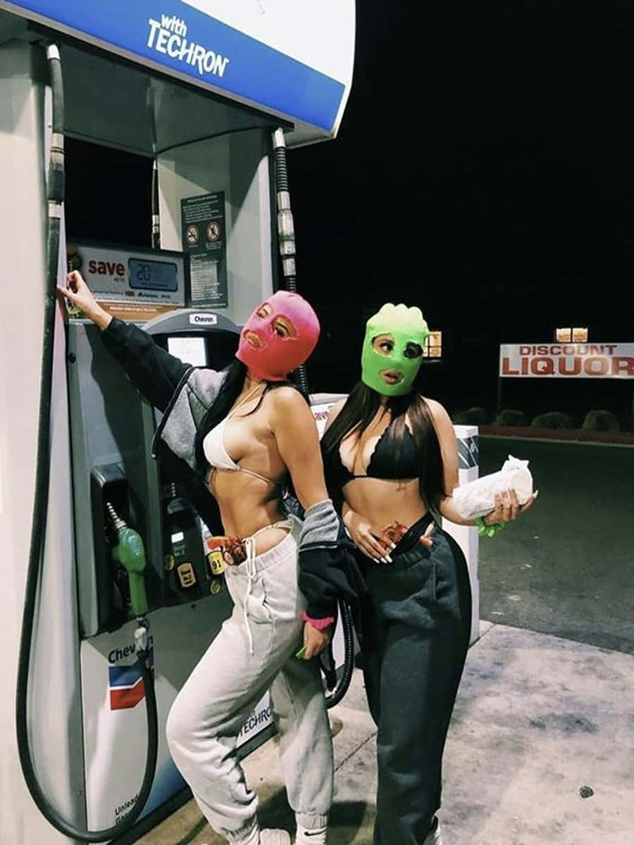 Duemodelli Di Ragazze Con Maschera Da Sci Alla Stazione Di Benzina Sfondo