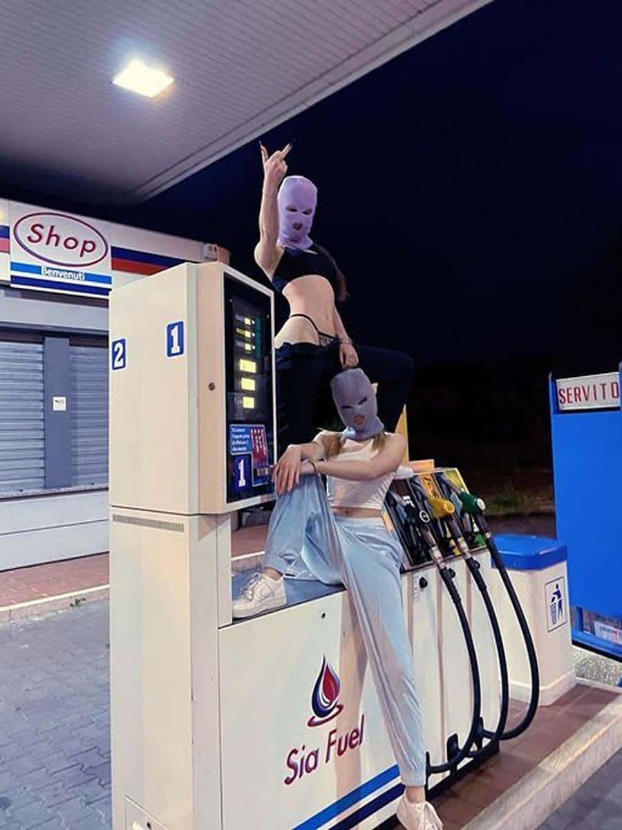 Modelpiger med ski-maske på pumpning brændstof baggrundsbillede Wallpaper
