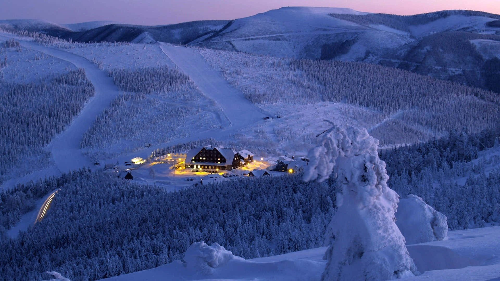 An aerial view of a snow-covered ski mountain surrounded by pristine nature Wallpaper