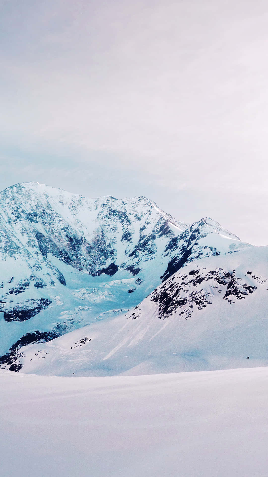 En person står på ski ned af en snebeklædt bjerg. Wallpaper