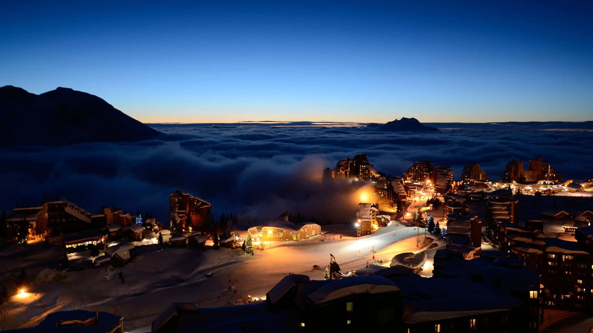 Majestic ski resort surrounded by snow-capped mountains Wallpaper