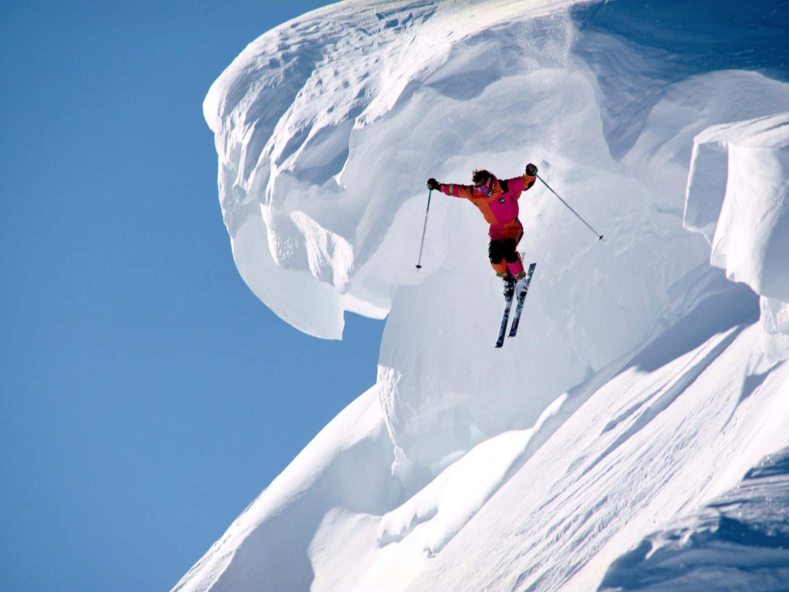 Skier Descending Down Ski Slope on Perfect Snowy Day Wallpaper