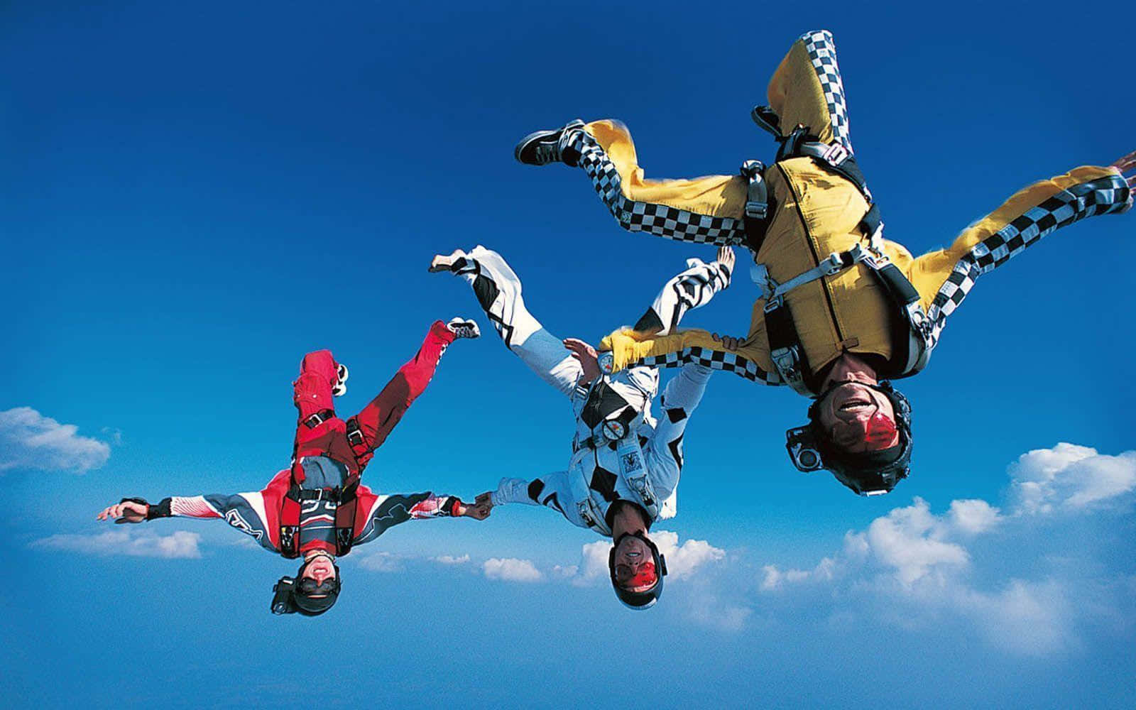 Dreipersonen In Fallschirmkleidung Fliegen In Der Luft.