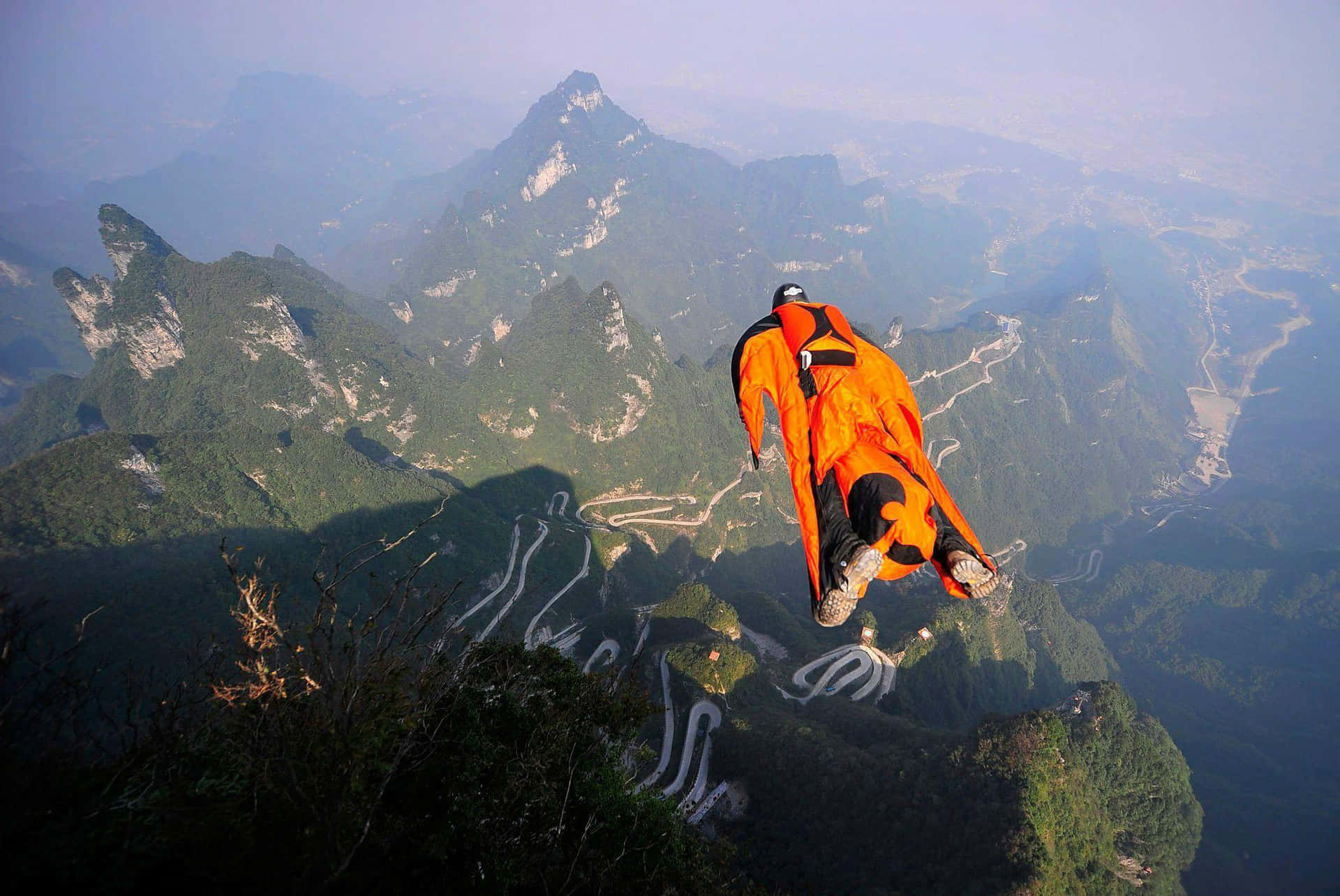 A Man Flying In The Air Over A Mountain