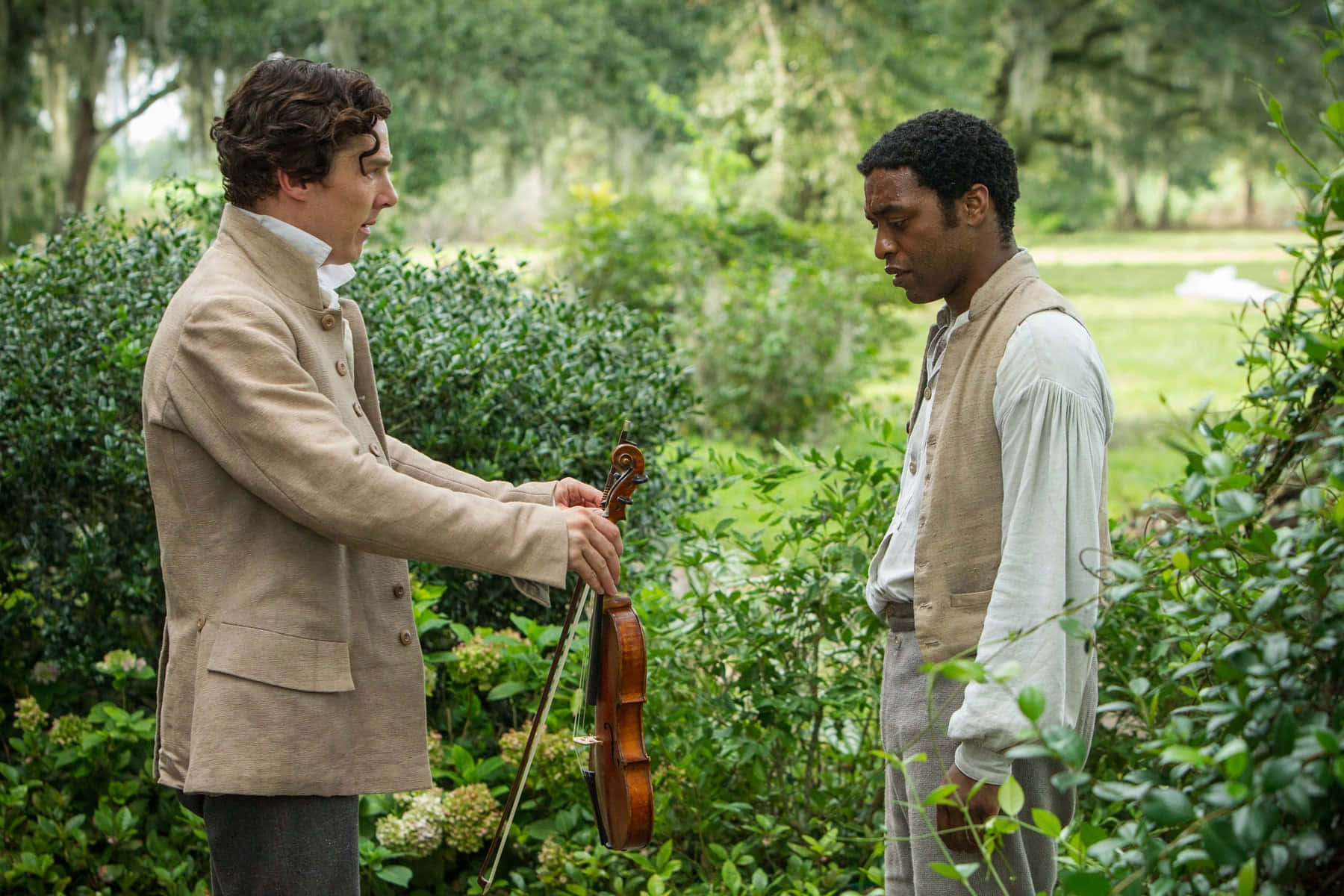 Two Men In A Garden Holding A Violin