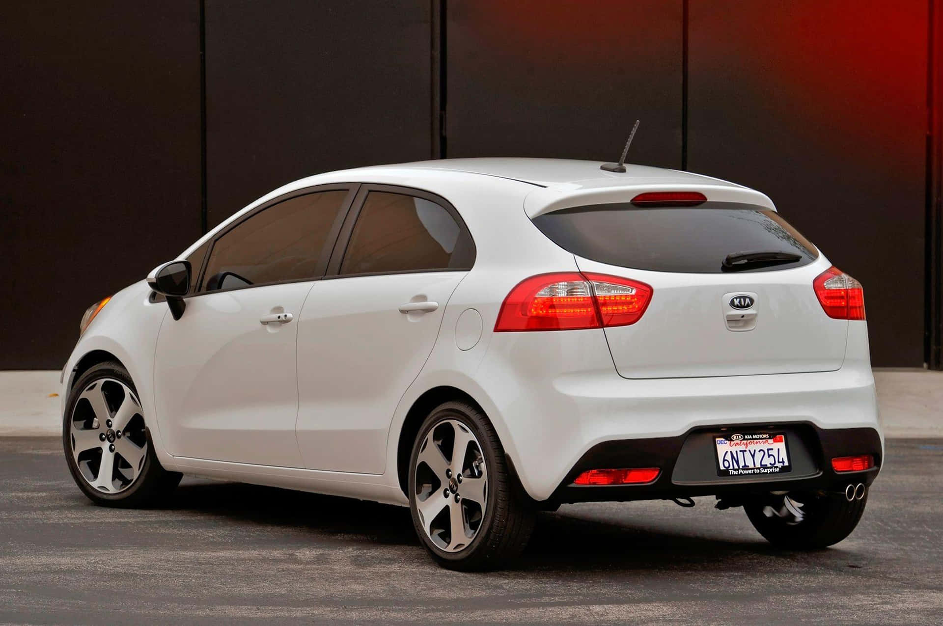 Sleek Red Kia Rio Parked On A Sunny City Street Wallpaper