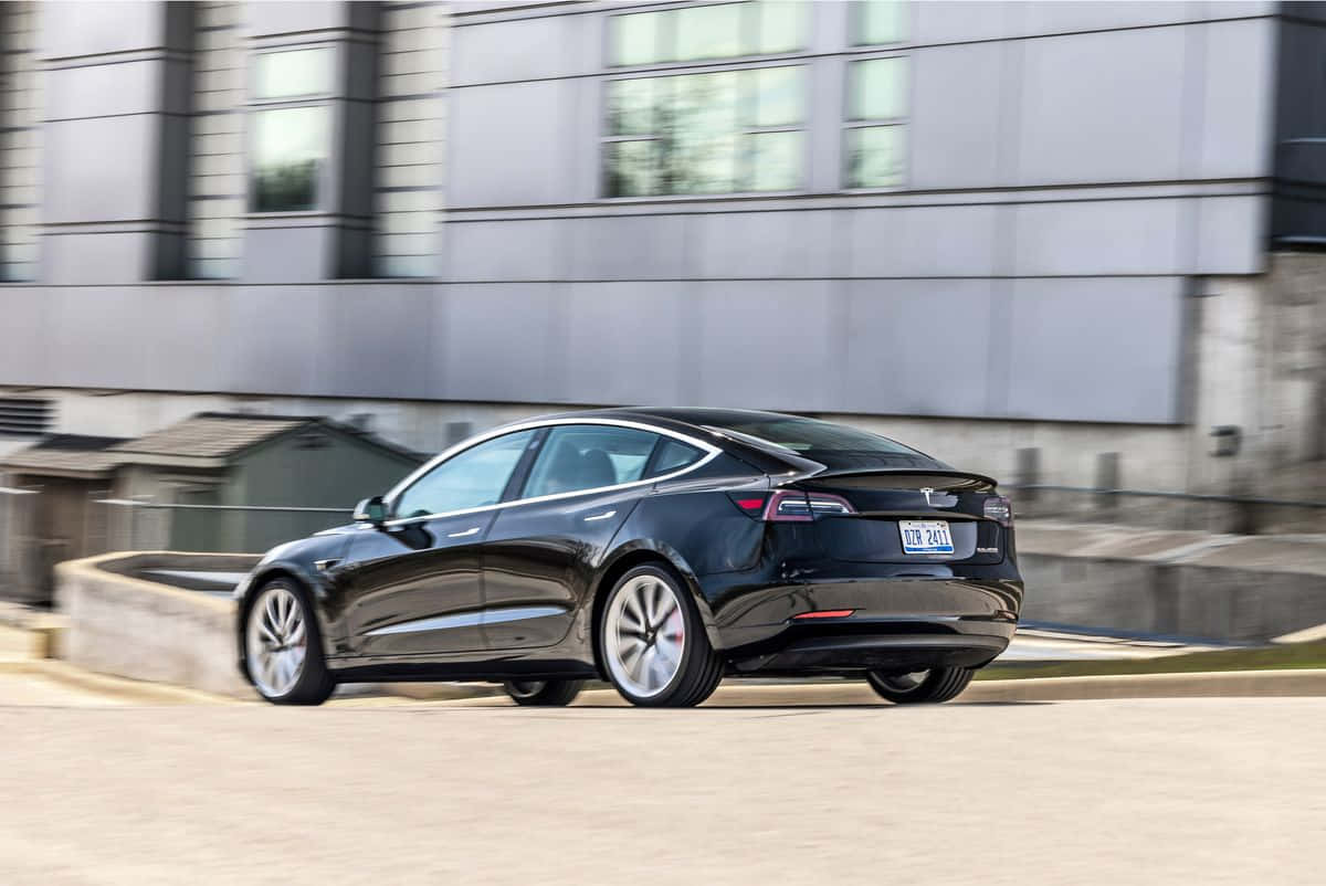 Sleek Tesla Model 3 Electric Car In Urban Setting Wallpaper
