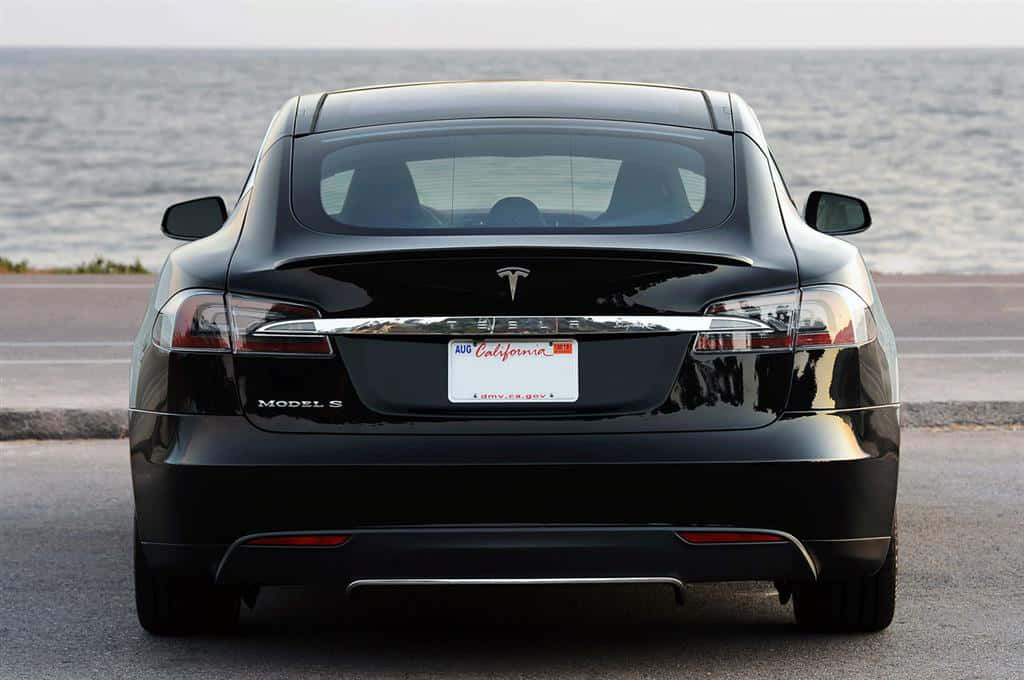 Sleek Tesla Model S Gliding Down A Road At Twilight Wallpaper