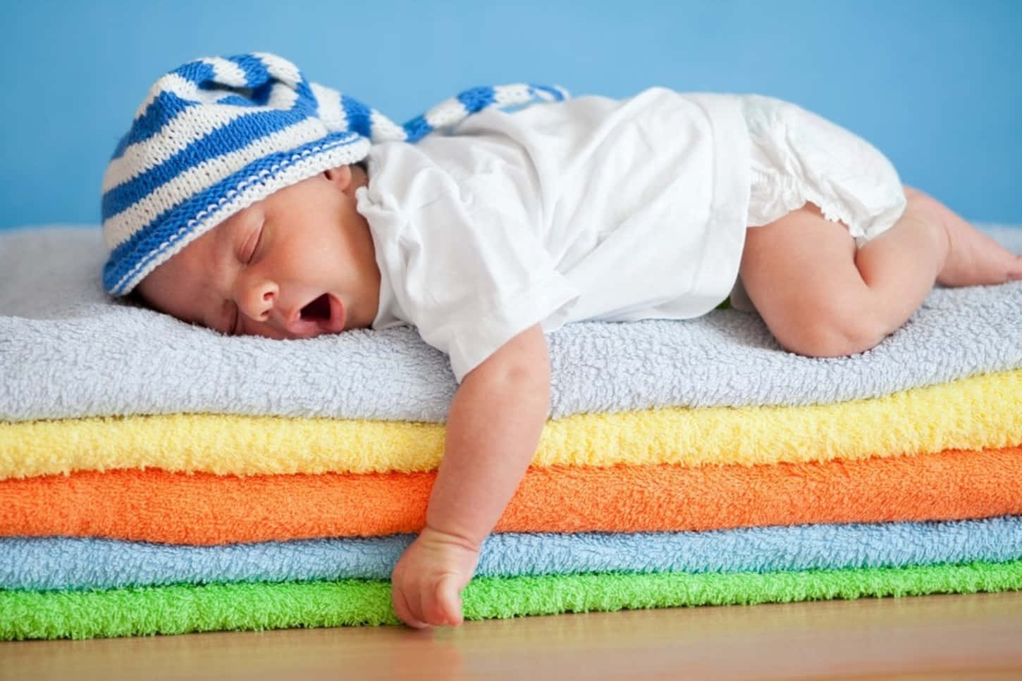 A Baby Sleeping On A Stack Of Colorful Towels