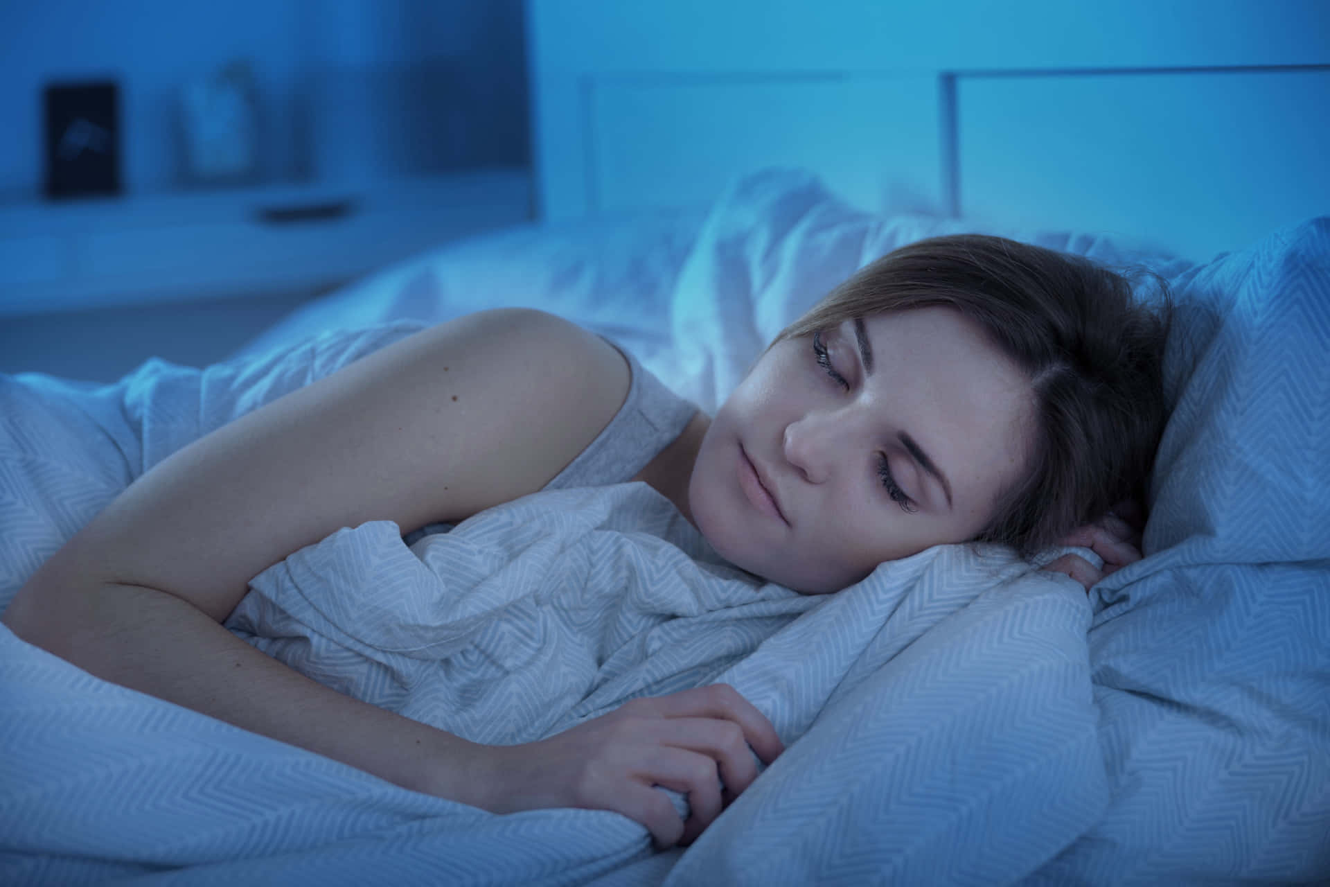 A Woman Sleeping In Bed With Blue Lights On