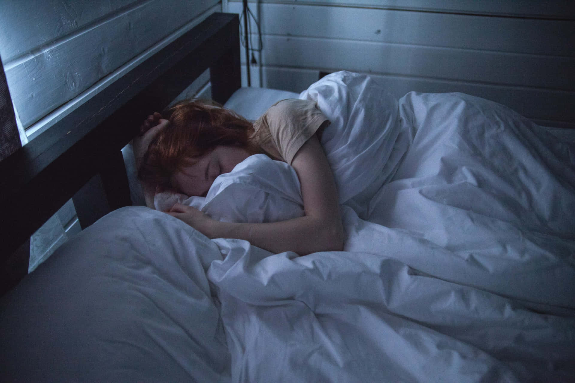 A Woman Sleeping In Bed With A White Blanket