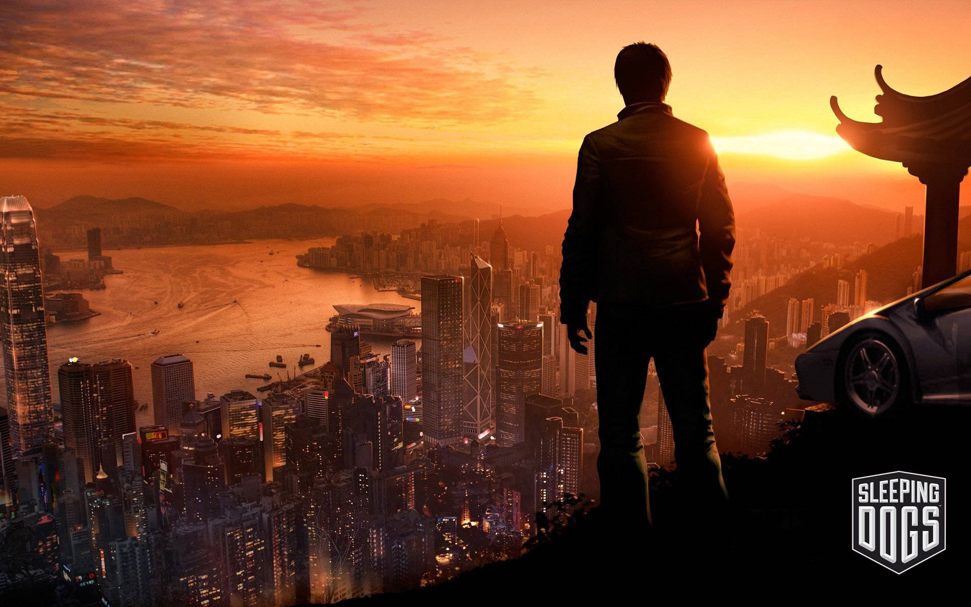 A Man Is Standing On A Hill Overlooking A City At Sunset Wallpaper