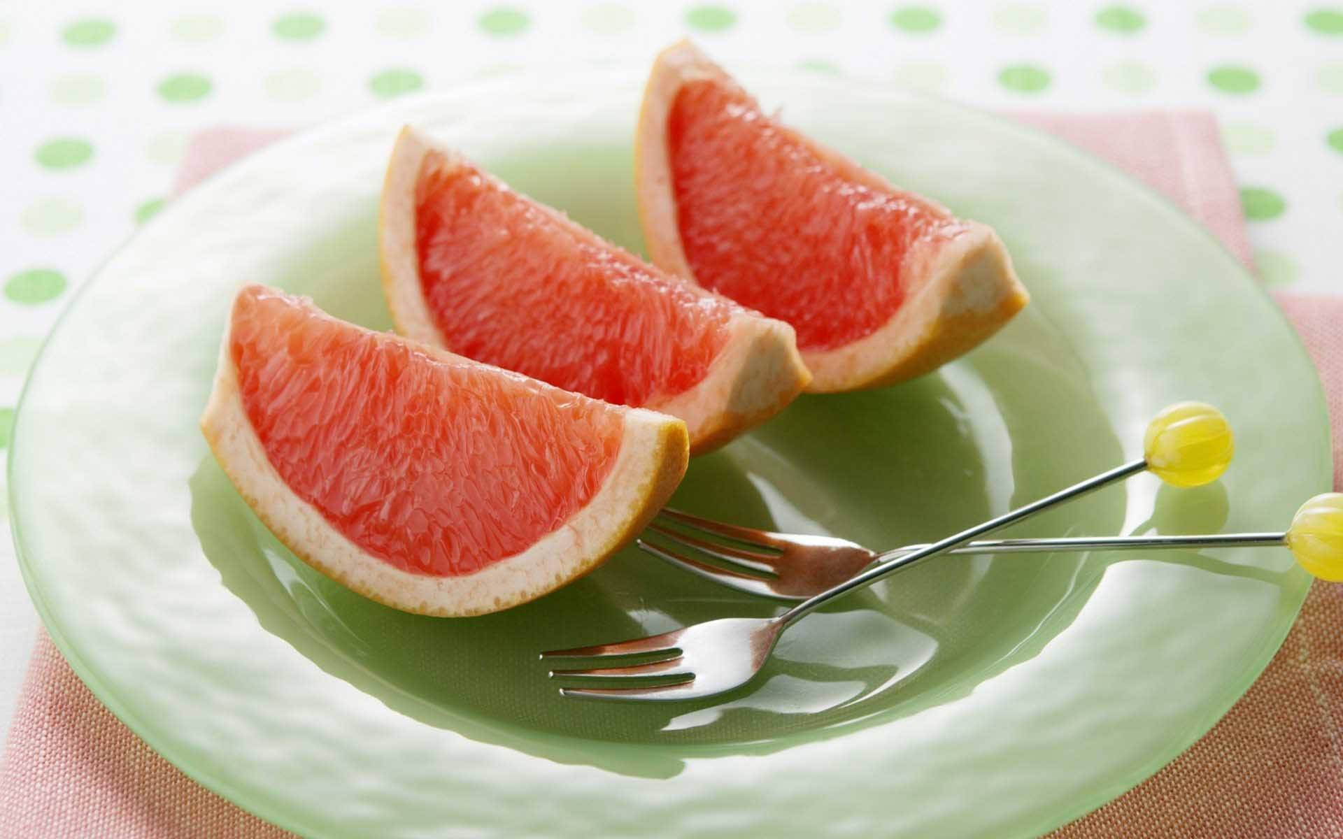 Sliced Grapefruits On A Plate With Forks Wallpaper