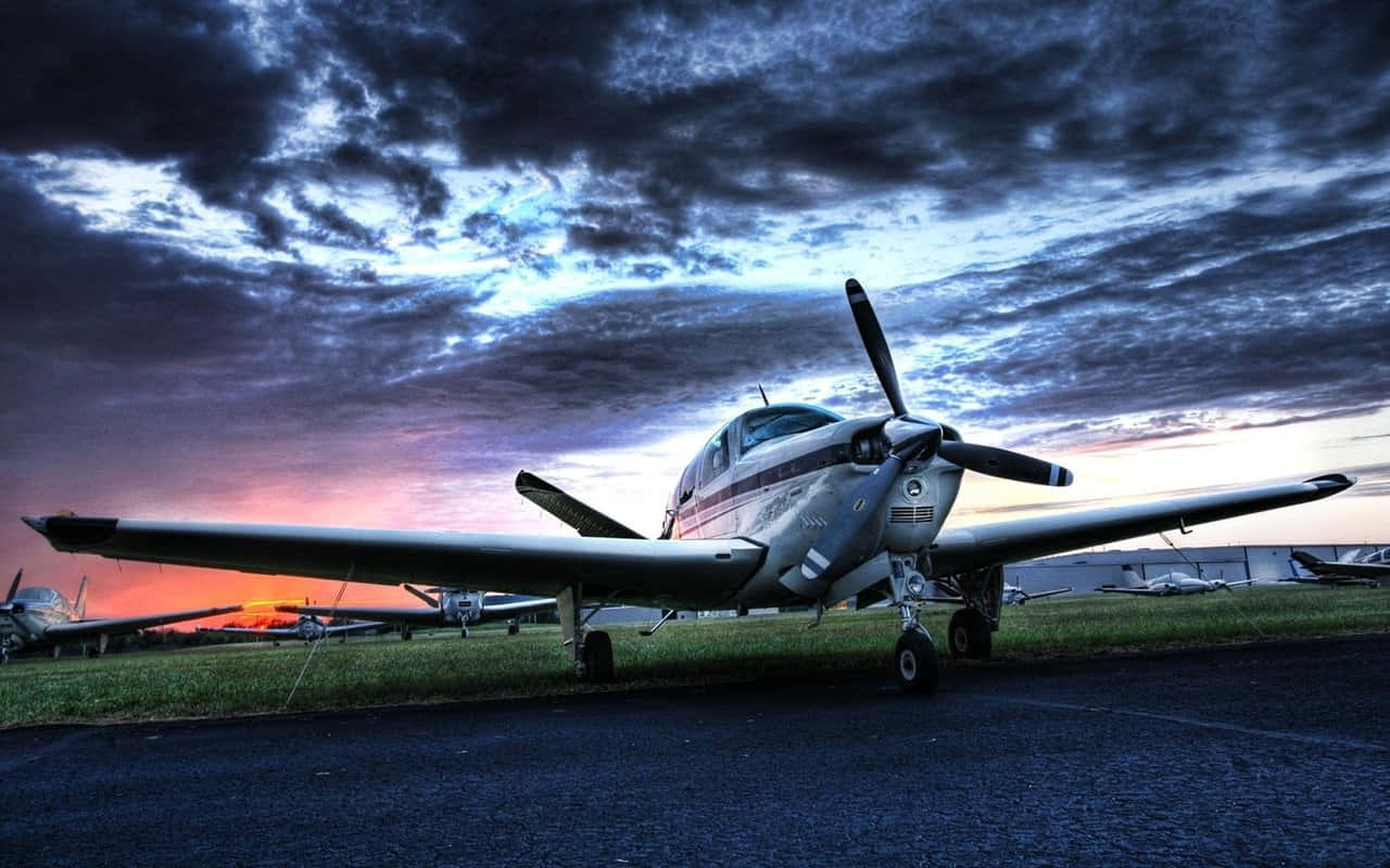 Hintergrundbildmit Kleinem Beechcraft Bonanza Flugzeug Bei Sonnenuntergang.